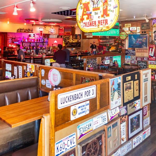 A lively Texaz Grill interior with booths, a bar, and walls covered in license plates and memorabilia.