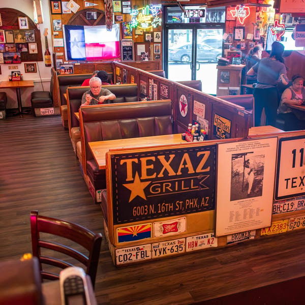 Diners seated in booths at Texaz Grill, with Texas-themed decor and neon signs filling the walls.
